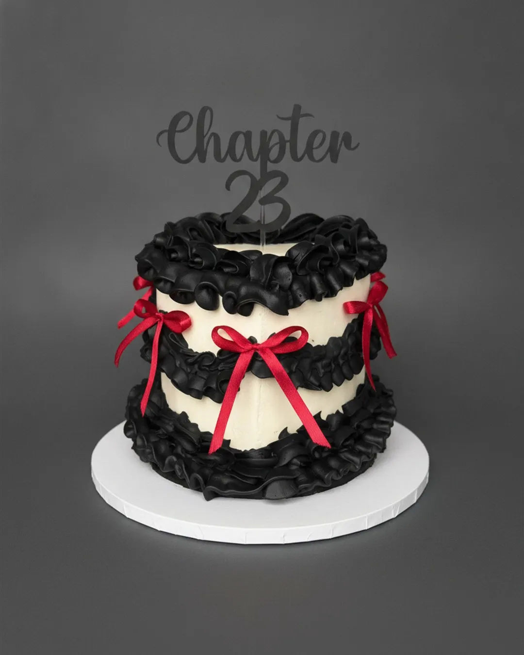 Black ruffled Lambeth cake decorated with red satin bows and a chapter number topper