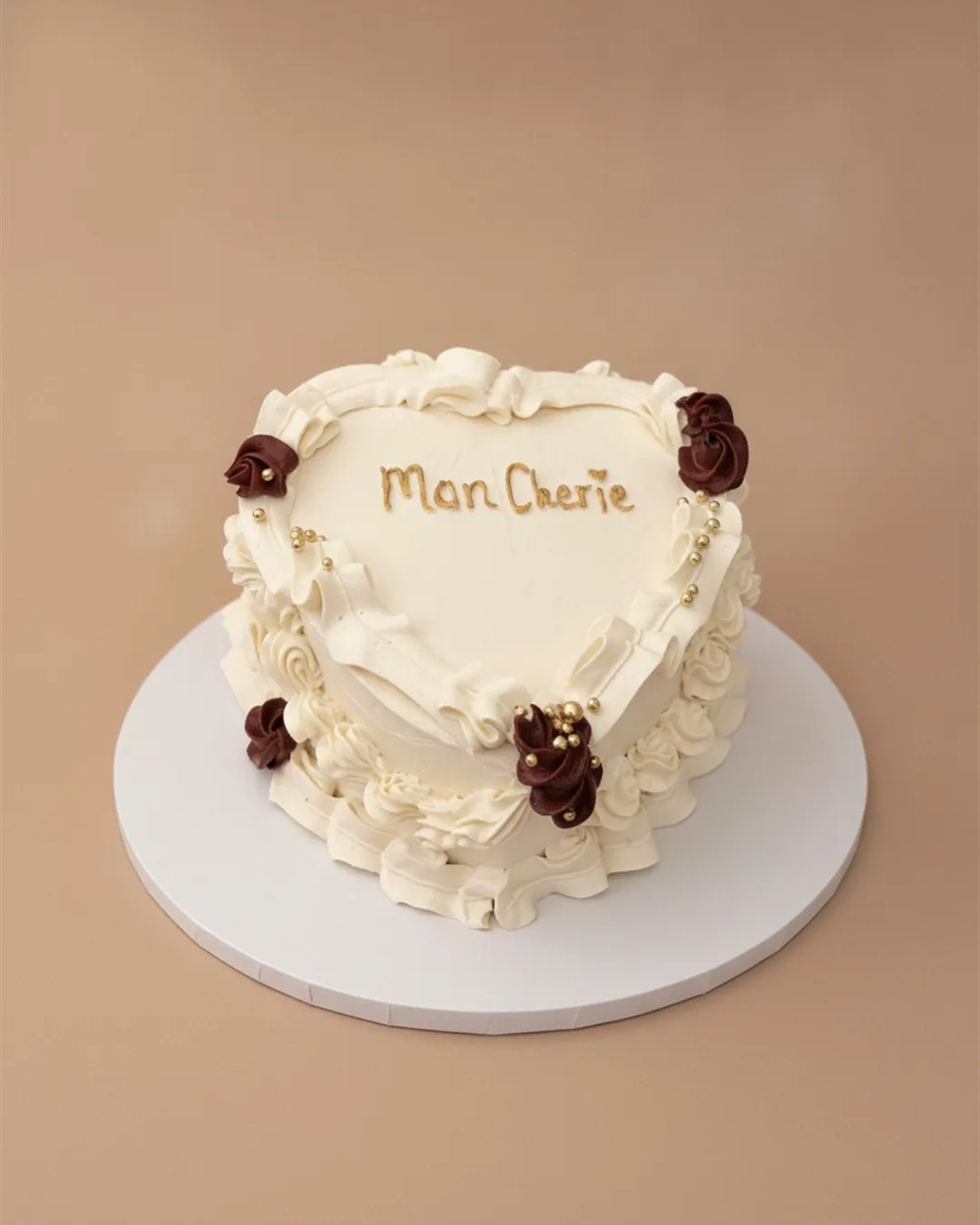 Ivory heart-shaped cake with burgundy sugar roses, gold beading and script lettering
