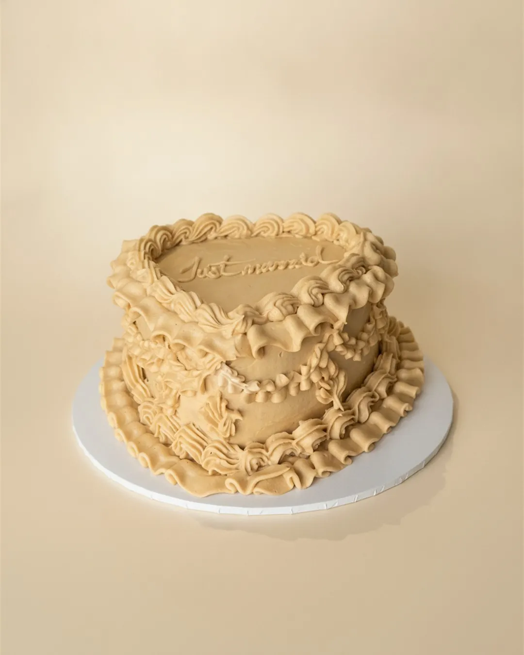 Caramel heart-shaped cake with vintage ruffle piping and Just Married lettering