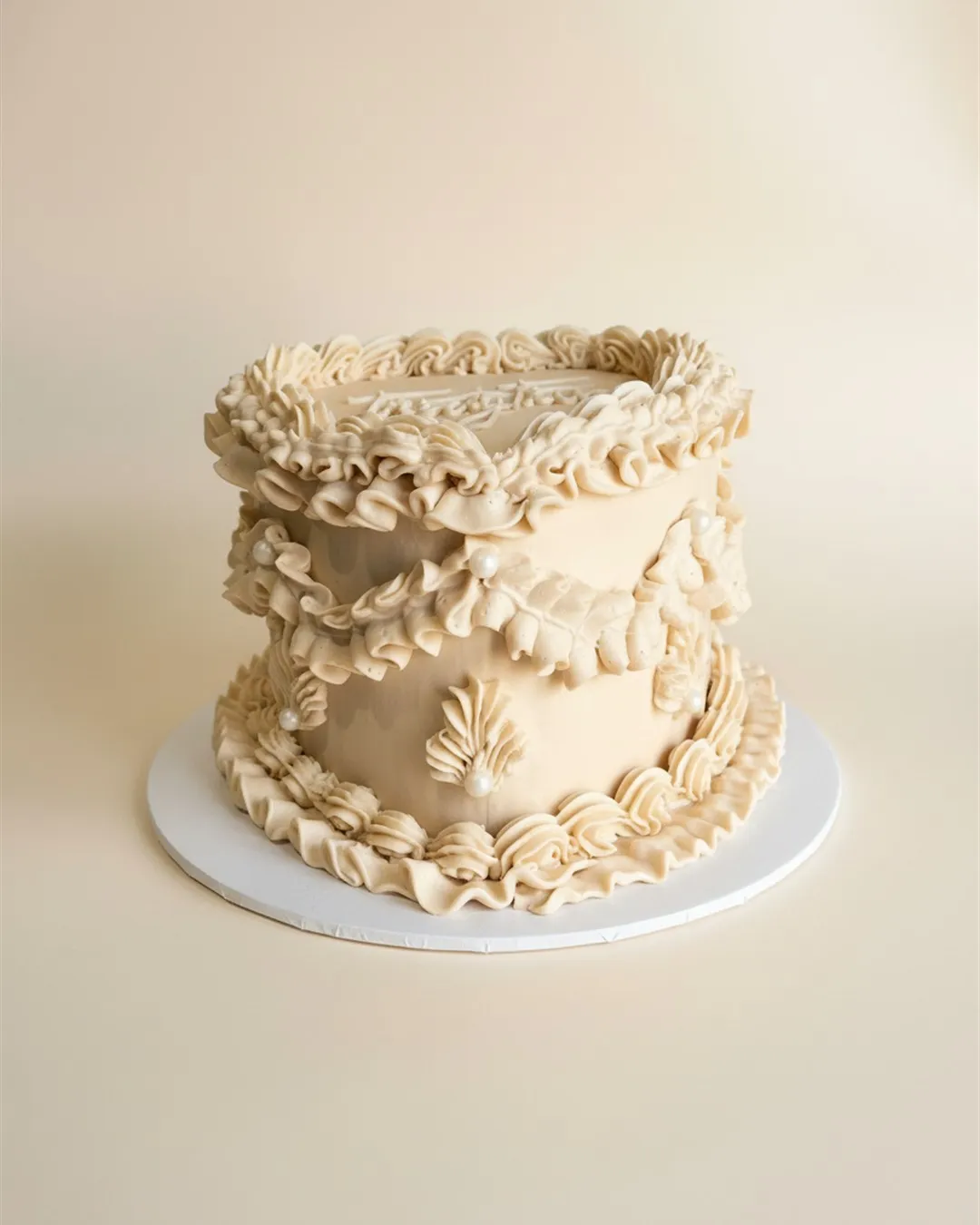 Caramel single-tier cake with vintage ruffle piping and a script twenty five topper