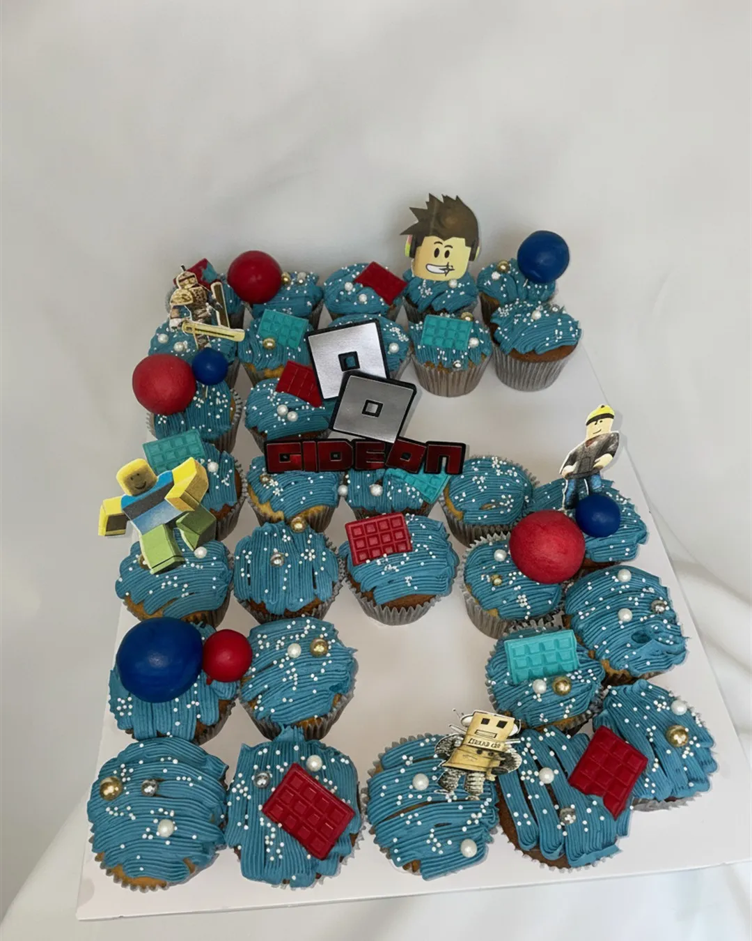 Pull-apart cupcakes arranged as a name and number with blue swirled buttercream and gaming toppers