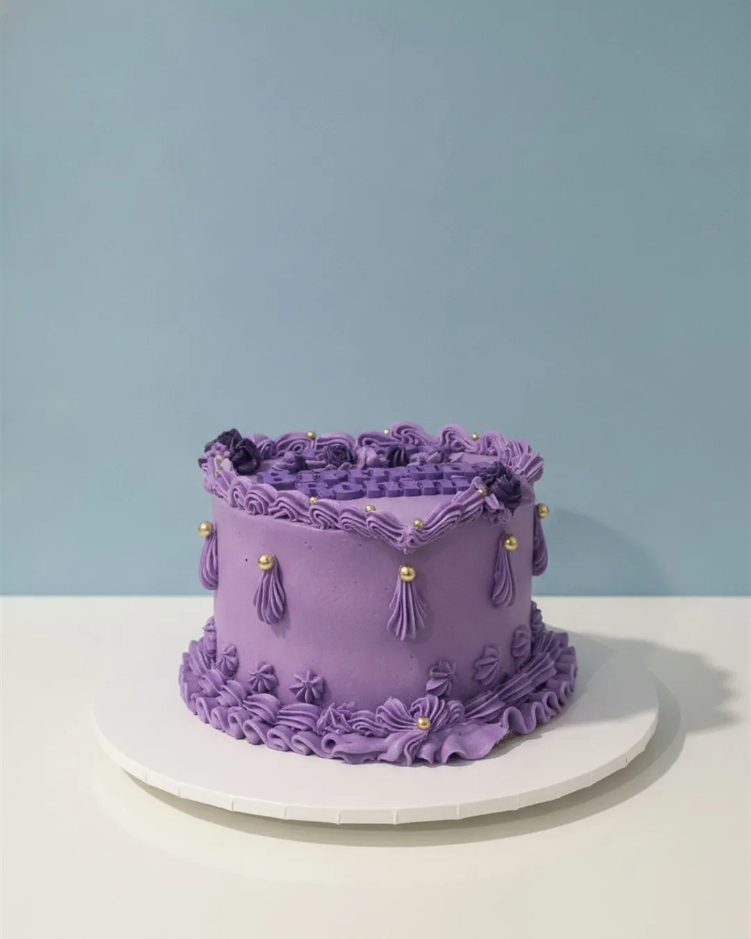 Single-tier lilac vintage cake with piped ruffles, tassels and gold beads