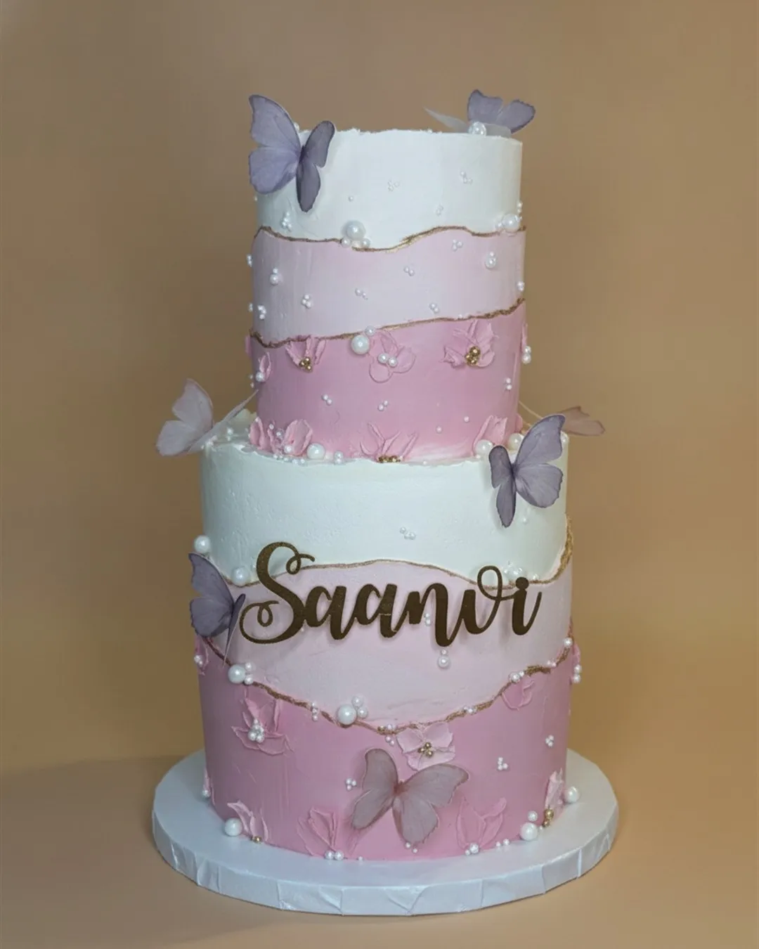 Two-tier lilac and pink ombre cake with sugar butterflies, pearls and a gold script name topper