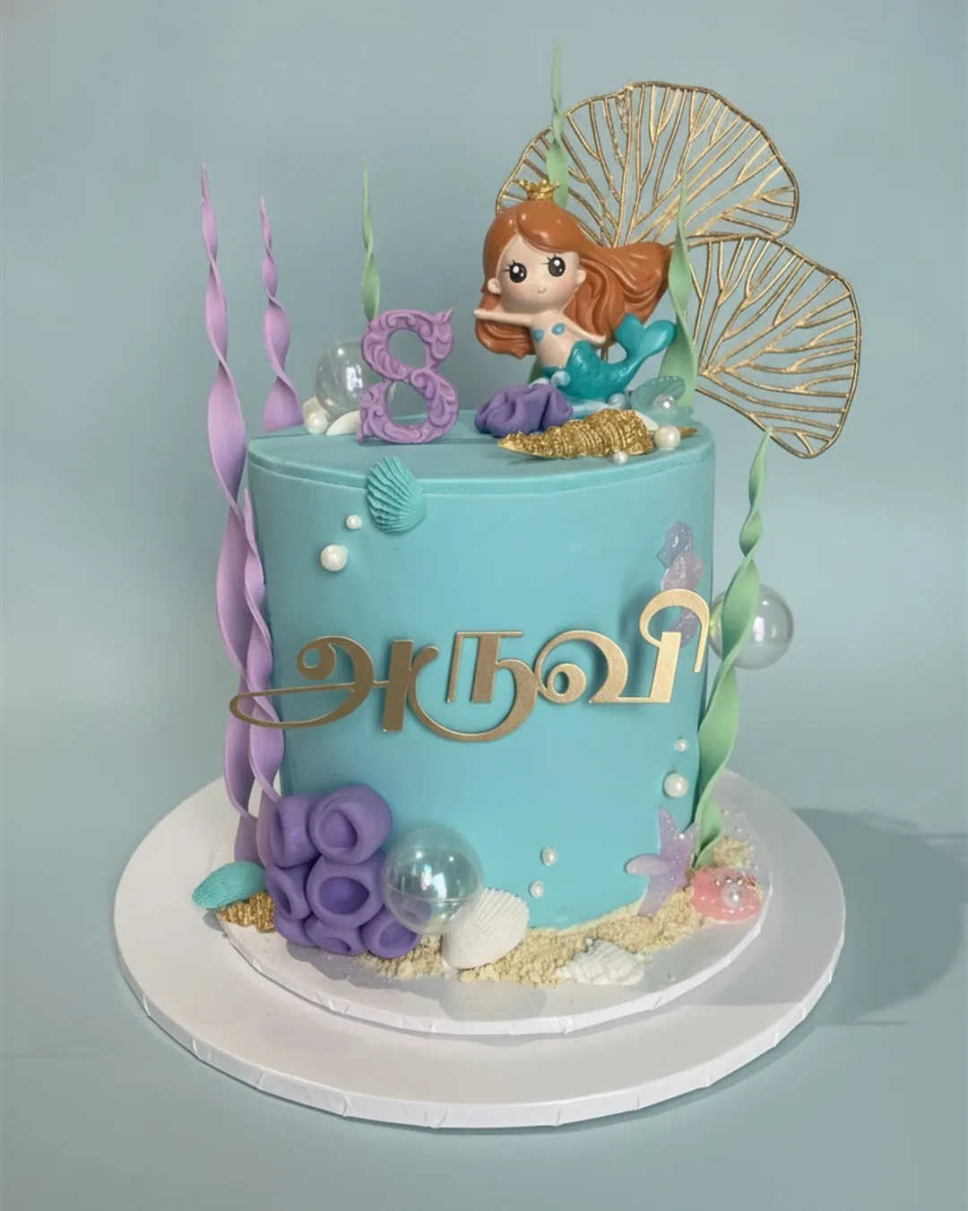Turquoise mermaid cake with a sugar mermaid figure, coral, shells, bubbles and gold fan detail