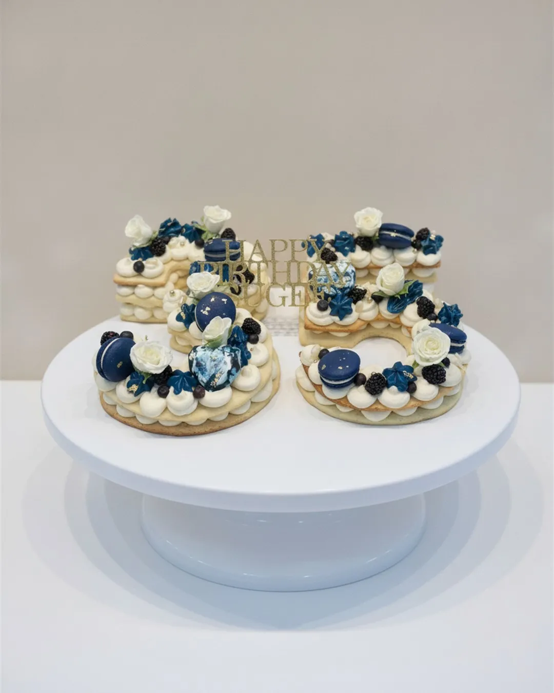 Number-shaped cream piped cakes topped with navy and white flowers and fresh blueberries