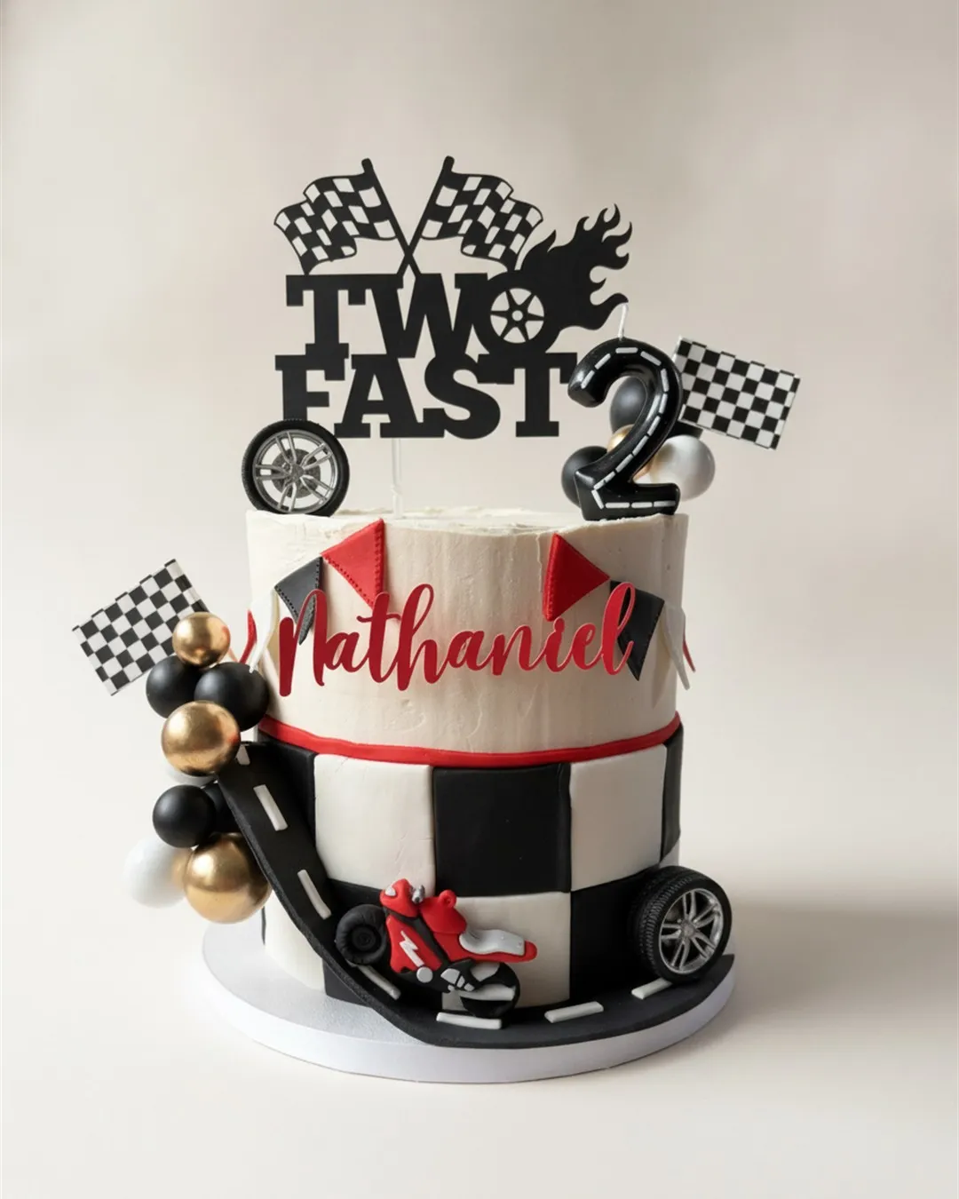 Two-tier red black and white racing cake with checkered flags, a race car and balloon toppers