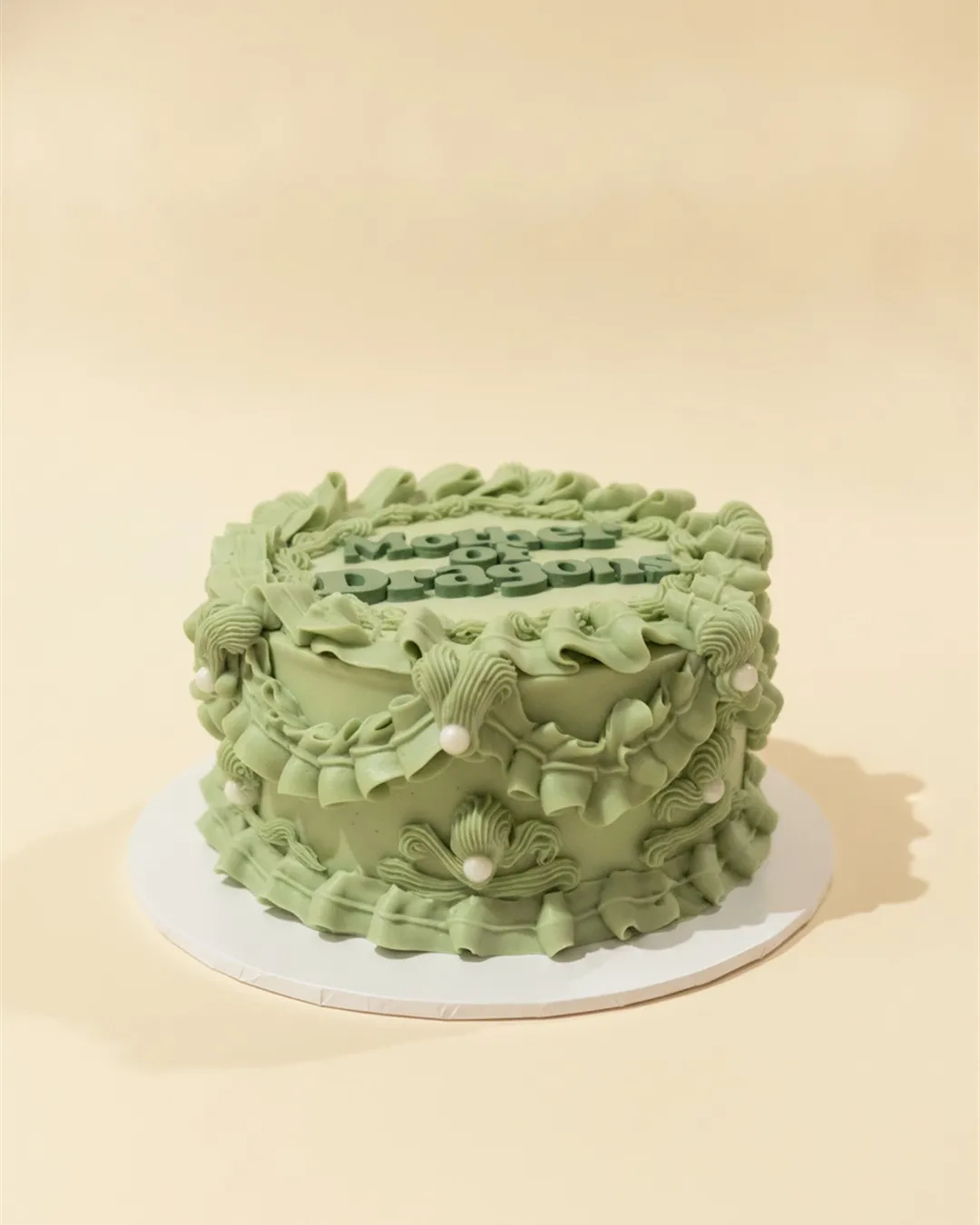 Sage green single-tier cake with vintage Lambeth ruffle piping and lettered topper