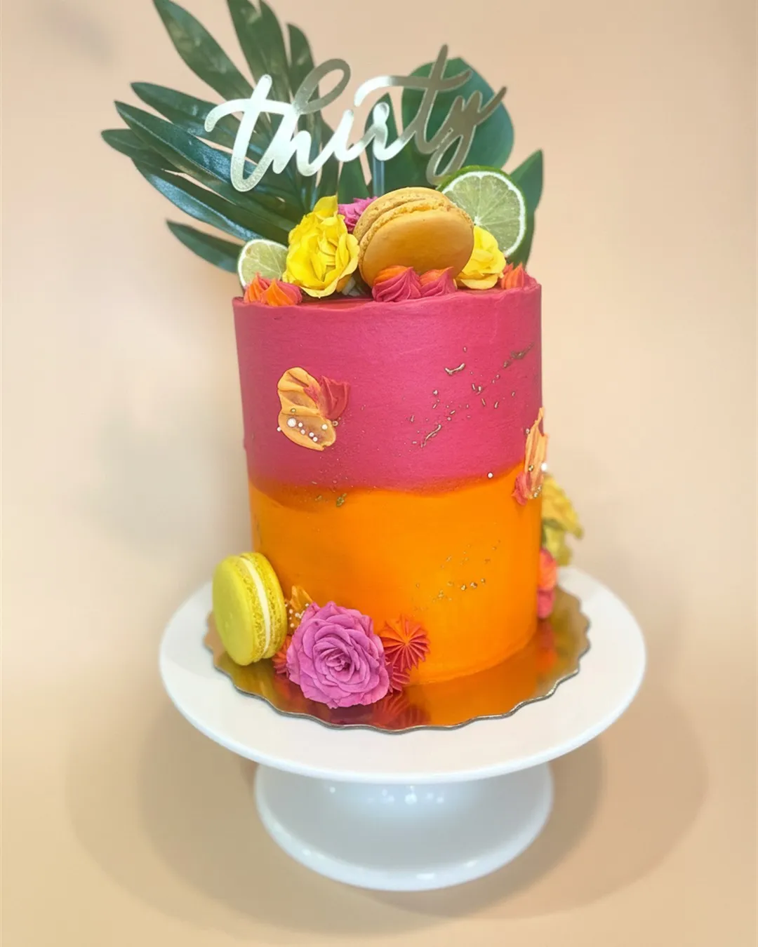 Pink and orange ombre cake with tropical leaves, macarons, citrus and bright sugar flowers