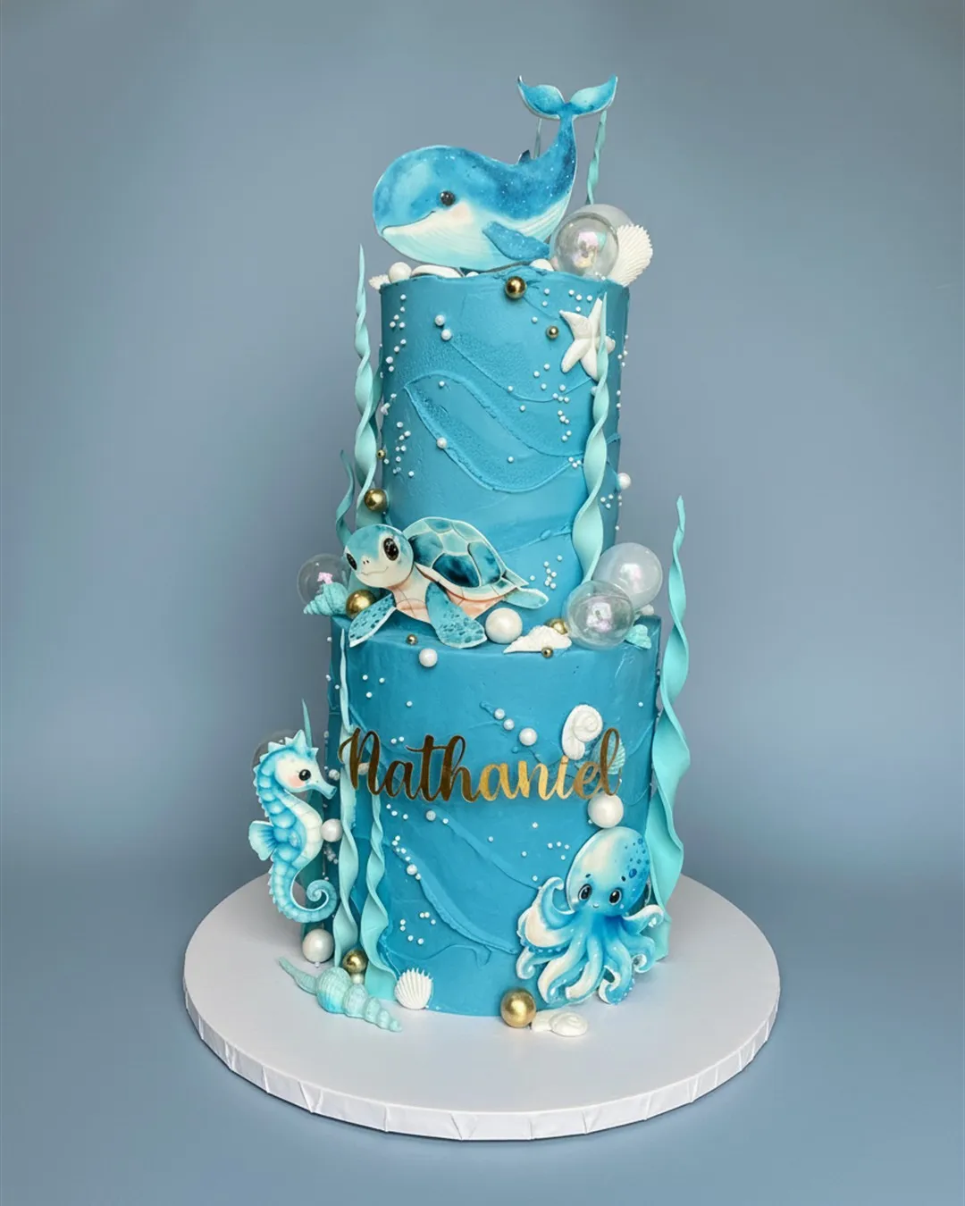 Two-tier blue and teal under the sea cake with a whale, turtle, octopus, seahorse and bubbles