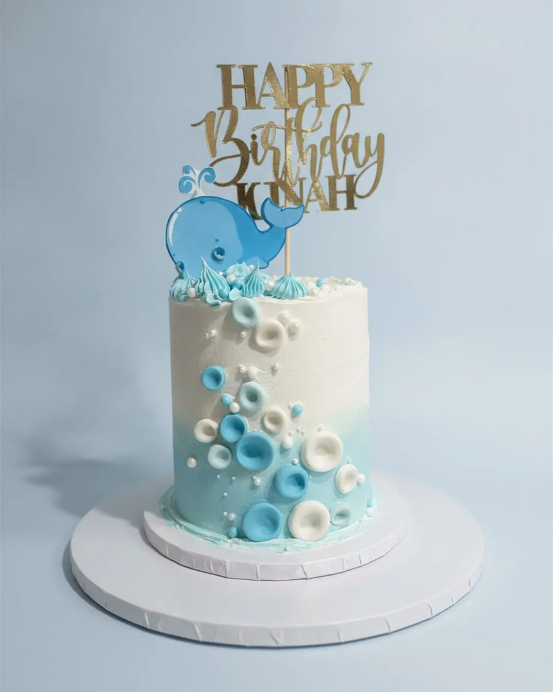 Blue and white ombre cake with sugar bubbles, pearls and a smiling whale topper