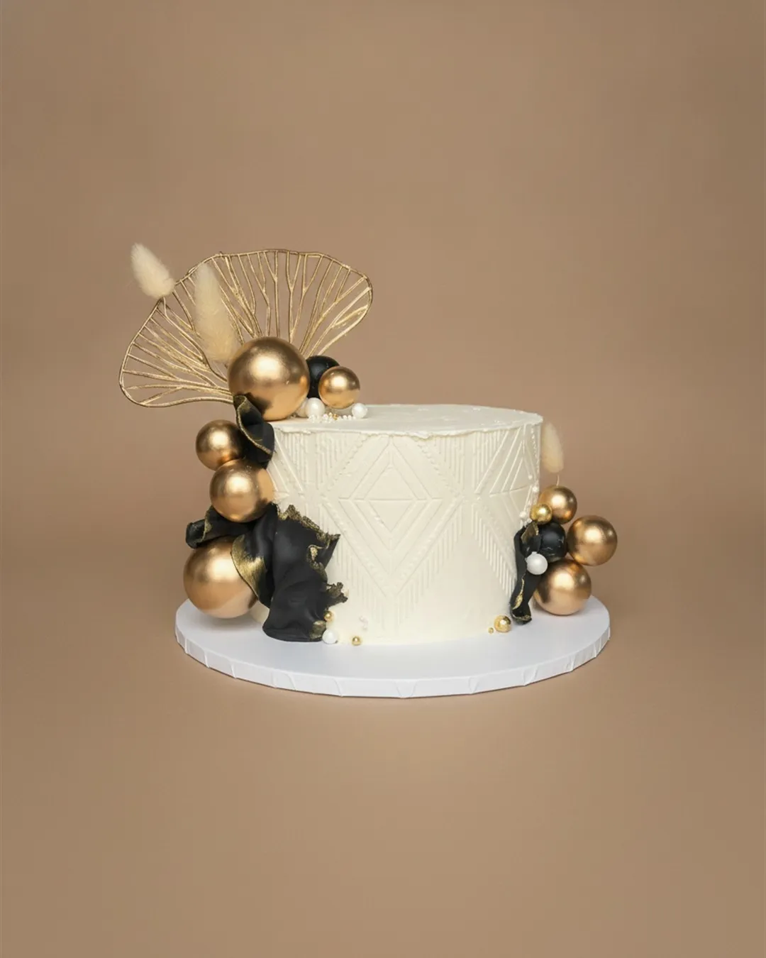 White geometric embossed celebration cake with gold spheres and black and gold sail decorations