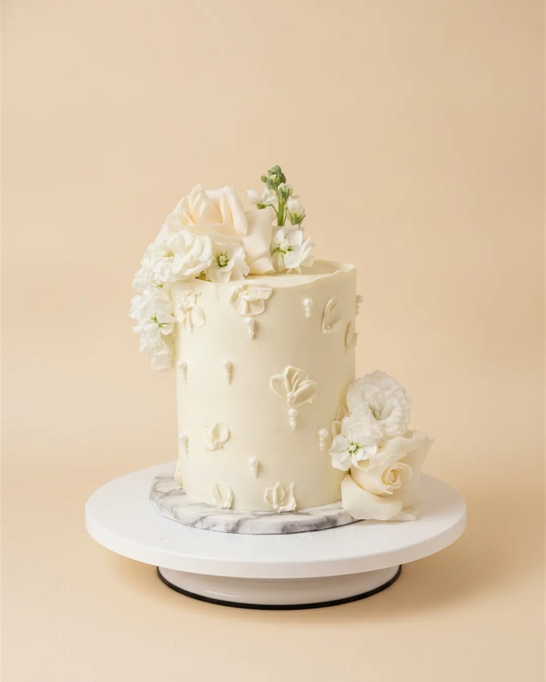 White cake with fresh roses and stock flowers, piped petals and sugar pearl detailing
